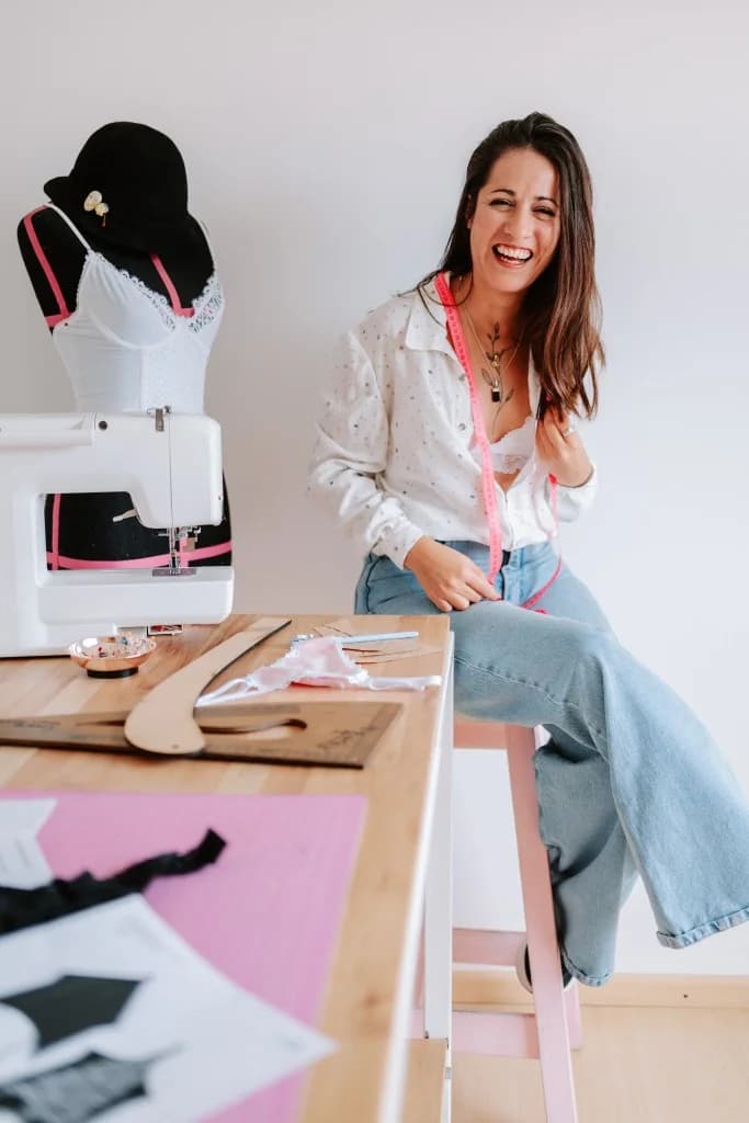 Barby en su taller de costura, sonriendo junto a su máquina y maniquí